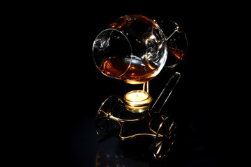 A glass of cognac on a special stand with candle for warming drink in the dark
