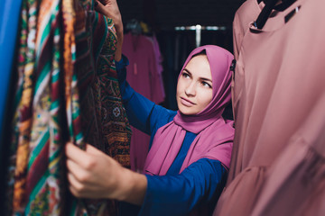 Obraz na płótnie Canvas Arab woman in traditional Muslim clothes buys a new dress in an Oriental store.