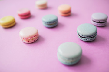 Obraz na płótnie Canvas Multicolored macaron or macaroon biscuits on pastel pink background, lying in three raws. Almond cookies of pastel colors. Overview.