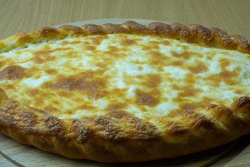 Freshly baked khachapuri with cheese on a wooden board.
