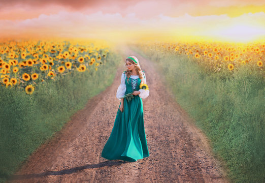 charming girl in green long dress with white shirt walks along road, lady with blond braids holds yellow flowers in hands, rural beauty returns home from field, art photo with pink sky at sunset