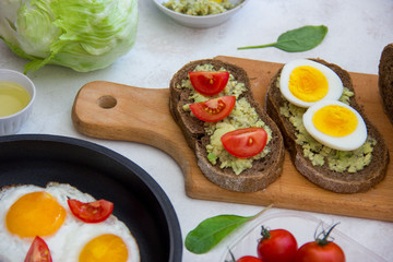 Tasty vegetarian healthy delicious breakfast with avocado, egg, tomato on wooden board.
