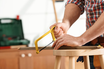 Man working with hand saw indoors, closeup. Home repair