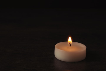 Obraz na płótnie Canvas Burning candle on dark background, space for text. Symbol of sorrow