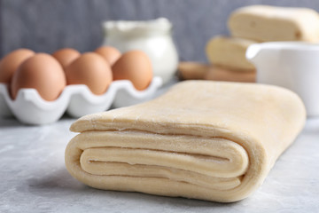 Raw puff pastry dough and ingredients on grey table