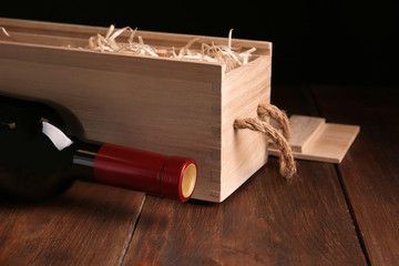 Open wooden crate with bottle of wine on table