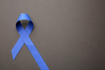 Blue ribbon on grey background, top view with space for text. Symbol of social and medical issues