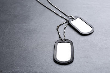 Blank military ID tags on grey stone surface, space for text