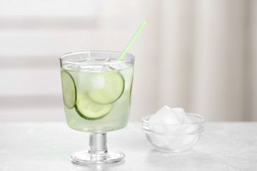 Glass of tasty cucumber martini cocktail with ice on table against indoors, space for text