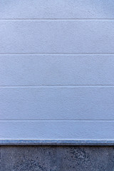 Ausschnitt Fassade als Hintergrund eines Hauses mit blauem Verputz und horizontal verlaufenden Sichtfugen als Gestaltungselement und Sockel aus dunklem Marmor