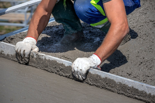 Worker Straighten And Smoothing Fresh Concrete On A Construction Site