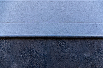Ausschnitt Fassade als Hintergrund eines Hauses mit blauem Verputz und horizontal verlaufenden Sichtfugen als Gestaltungselement und Sockel aus dunklem Marmor