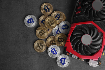 Modern video card and bitcoins on grey table, top view with space for text