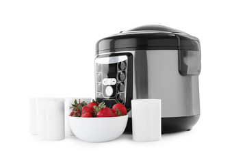 Modern multi cooker with cups of homemade yogurt and strawberries isolated on white