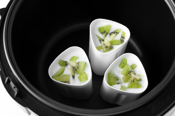 Cups of homemade kiwi yogurt in modern multi cooker, closeup view