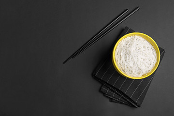 Fototapeta na wymiar Cooked rice noodles served on black table, flat lay. Space for text