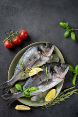 Top view of two raw dorado fishes on dark grey background