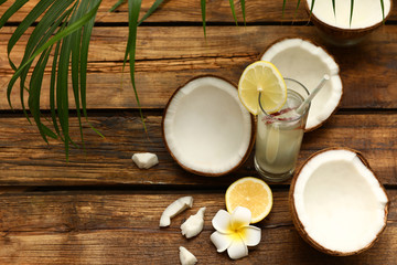 Composition with glass of coconut water and lemon on wooden table. Space for text