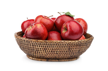 Wicker bowl of ripe juicy red apples with leaf on white background