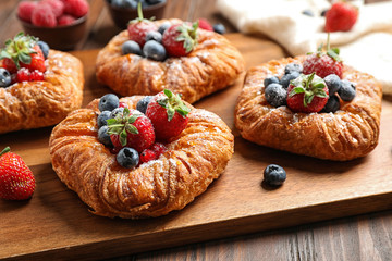 Fresh delicious puff pastry with sweet berries on wooden board, closeup