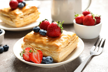 Fresh delicious puff pastry with sweet berries on grey marble table, closeup