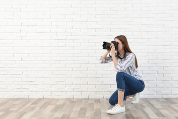 Professional photographer taking picture near white brick wall. Space for text - obrazy, fototapety, plakaty