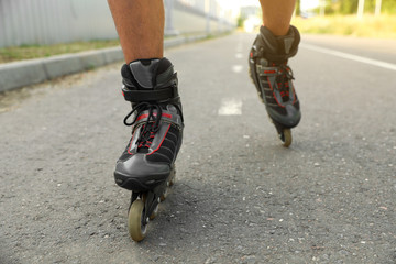 Young man roller skating outdoors, closeup. Recreational activity