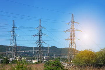 Electricity transmission pylons against blue sky. High voltage electricity poles in mountains.
