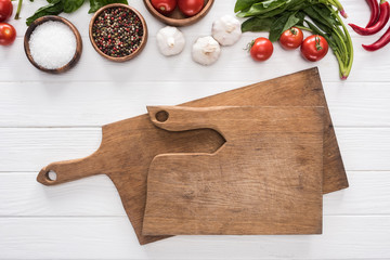 top view of cutting boards, cherry tomatoes, greenery, chili peppers, salt, garlics and spices