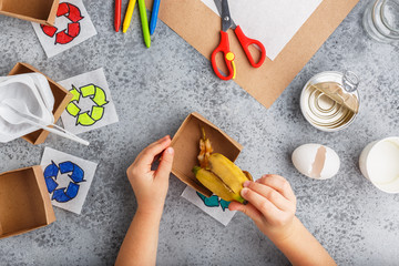 Girl hands are making recycling game in paper on grey background colourful
