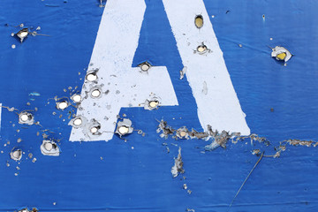 The road sign of the village, in the place of hostilities. Bullet holes in metal.
