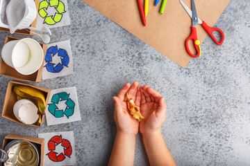 little girl hands are holding a stump of an apple on grey background recycle concept