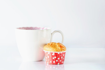 A white mug and homemade cupcakes on a white background, close up, macro