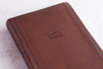 A Brown Leather Holy Bible on a White and Gray Concrete Surface