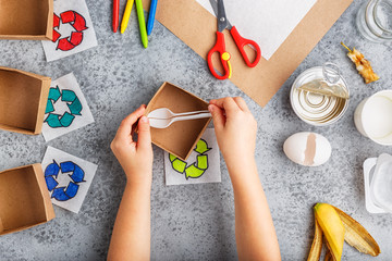 Girl hands are making recycling game in paper on grey background colourful
