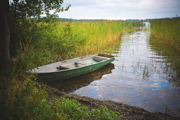 Naklejka na ściany i meble Fishing boat in a calm lake water.Old wooden fishing boat in a still lake water.
