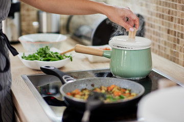 Dedicated Caucasian woman opening boiling pot. Vegetarian dinner preparation concept.