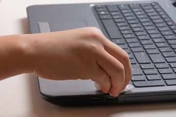 A teenager boy of 10 years old is cleaning his laptop with a special cloth and cleaning agent.
