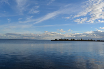 Fototapeta premium Picturesque landscape with blue river and light clouds in the sky. Panoramic view.