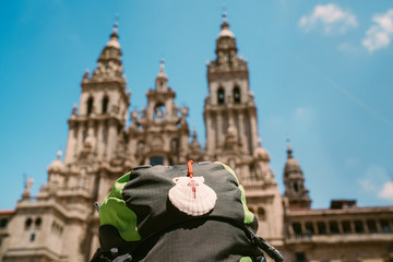 Pilgrim's backpack with famous pilgrims' mascot and sign seashell with Cross of Saint James at  on...