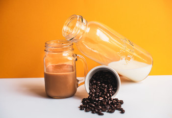 Iced Coffee and milk on yellow background 