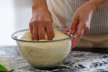 The woman is kneading  the dough.