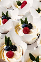 Berry cupcakes with filling in box. Dessert for birthday, wedding, celebration. Decoration in chocolate tone.