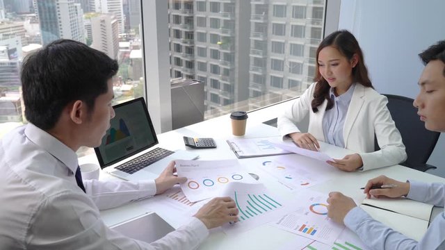 Asian business team discussing various plan charts and graphs at meeting room in modern city office