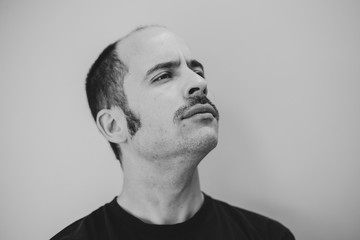 Naklejka premium White man with a prominent mustache looking into the distance against a seamless background