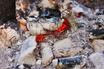 Bonfire embers texture close-up. Background of fireplace with gloving embers. Close up view on smouldering fire.