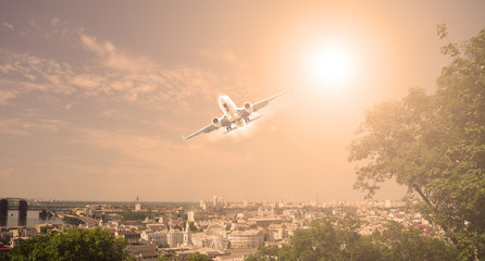 The plane over the city and plants. sunset.
