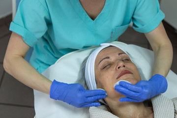 Naklejka premium Portrait of middle aged woman having face treatment at beauty clinic