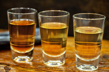 Several glasses of brazilian cachaça isolated on rustic wooden background, variations and types of brazil cachaça, typical drink from brazil.