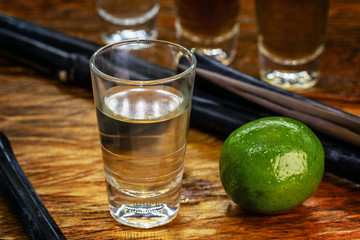A glass of brazilian cachaça isolated on rustic wooden background, bar drink.